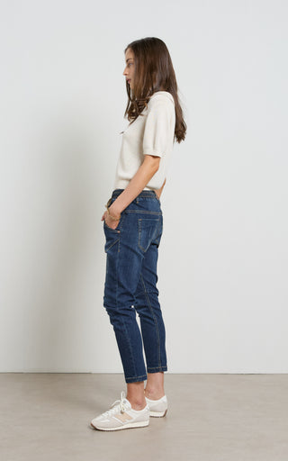 Woman wearing a Dark Blue Indigo jogger jeans with elasticated wait and drawstring standing against a white background