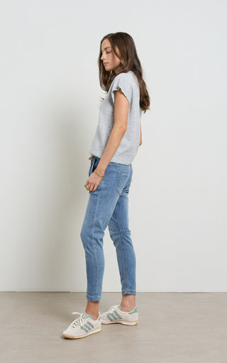 Woman wearing a blue jogger jeans with elasticated wait and drawstring standing against a white background