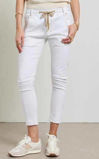Woman wearing a White jogger jeans with elasticated wait and drawstring standing against a white background