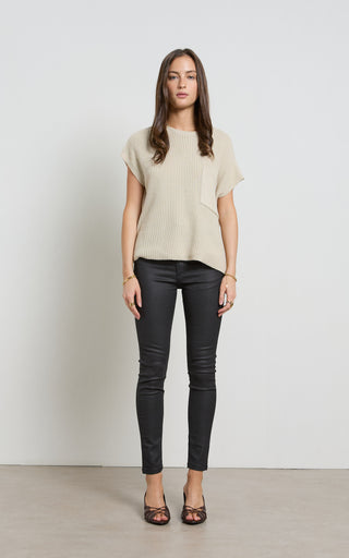 Woman wearing a leather like coated black Skinny Jeans standing against a white background