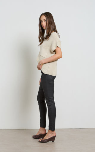 Woman wearing a leather like coated black Skinny Jeans standing against a white background