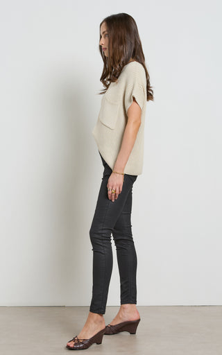 Woman wearing a leather like coated black Skinny Jeans standing against a white background