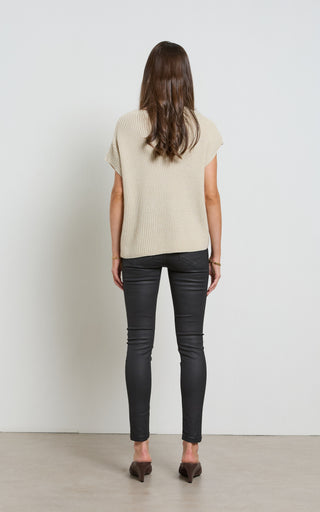Woman wearing a leather like coated black Skinny Jeans standing against a white background