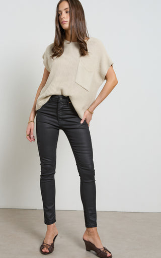 Woman wearing a leather like coated black Skinny Jeans standing against a white background