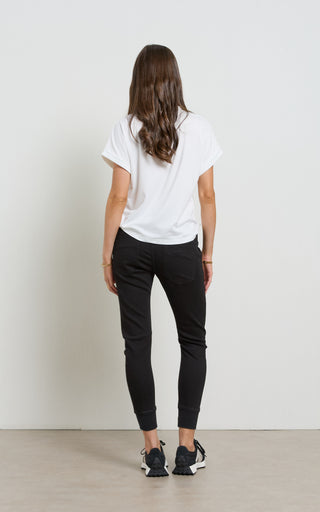 Woman wearing a white t-shirt and black pants against a plain white background