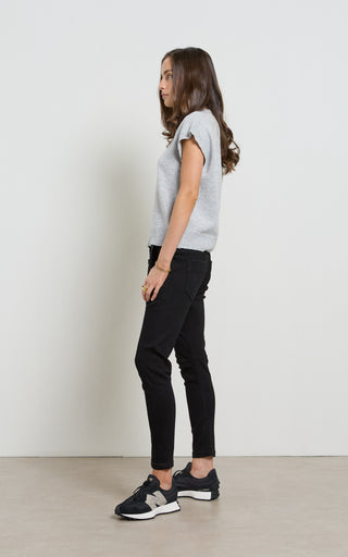 Woman wearing a gray sweater and black pants against a white background