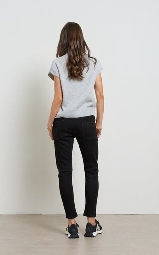 Woman wearing a light gray t-shirt and black pants against a white background