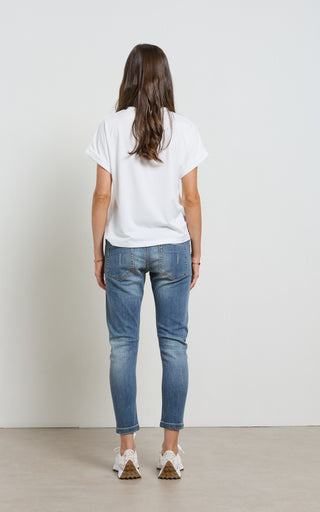 Woman wearing a Mid Blue Denim jogger jeans with elasticated wait and drawstring standing against a white background