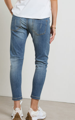 Woman wearing a Mid Blue Denim jogger jeans with elasticated wait and drawstring standing against a white background
