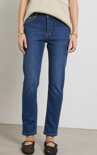 Woman wearing a straight leg mid blue stretch denim jeans standing against a white background