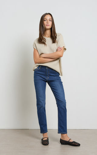 Woman wearing a straight leg mid blue stretch denim jeans standing against a white background