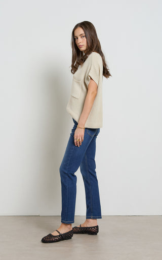 Woman wearing a straight leg mid blue stretch denim jeans standing against a white background
