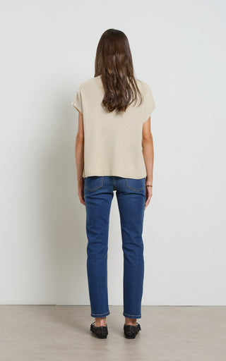 Woman wearing a straight leg mid blue stretch denim jeans standing against a white background
