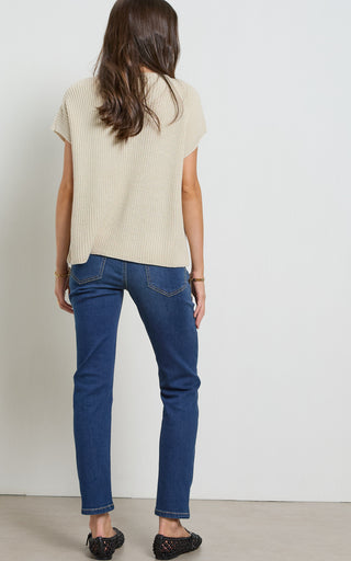 Woman wearing a straight leg mid blue stretch denim jeans standing against a white background