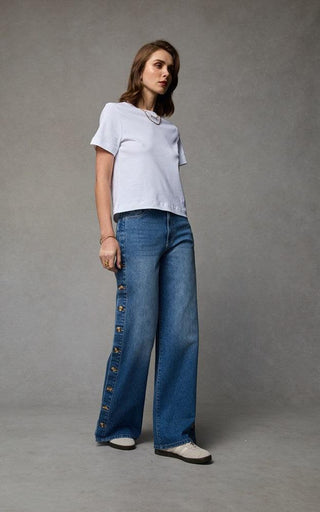 Woman wearing a wide leg jeans with horn button opening on the outer seam