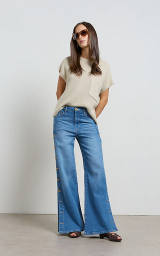 Woman wearing a wide leg jeans with horn button opening on the outer seam