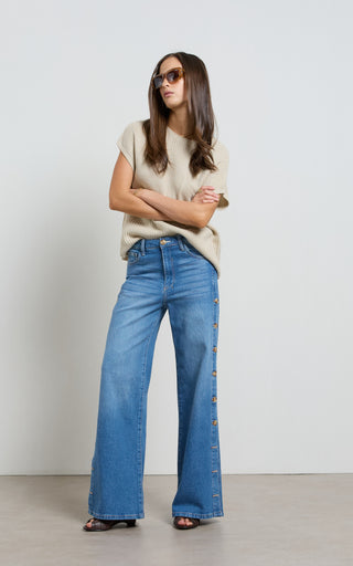 Woman wearing a wide leg jeans with horn button opening on the outer seam