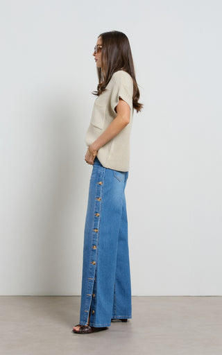 Woman wearing a wide leg jeans with horn button opening on the outer seam