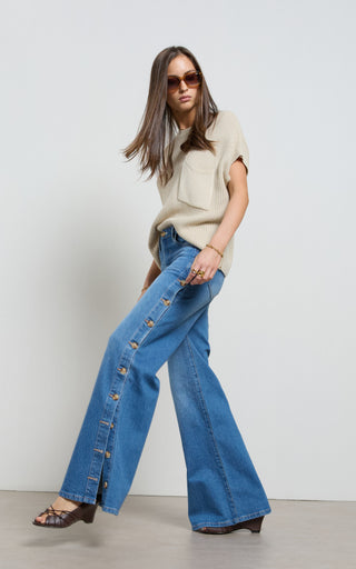 Woman wearing a wide leg jeans with horn button opening on the outer seam