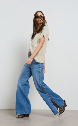 Woman wearing a wide leg jeans with horn button opening on the outer seam