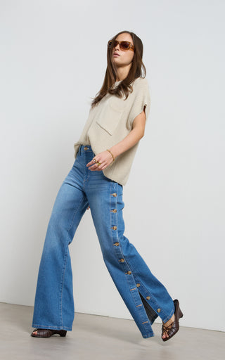 Woman wearing a wide leg jeans with horn button opening on the outer seam