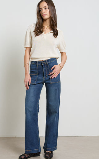 Woman wearing a wide leg dark blue stretch denim jeans standing against a white background