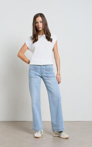 Woman wearing a wide leg light blue stretch denim jeans standing against a white background