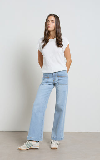 Woman wearing a wide leg light blue stretch denim jeans standing against a white background