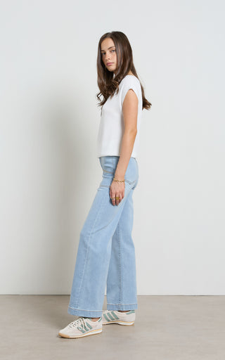 Woman wearing a wide leg light blue stretch denim jeans standing against a white background