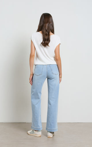 Woman wearing a wide leg light blue stretch denim jeans standing against a white background