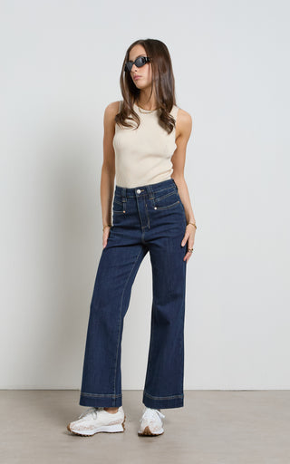 Woman wearing a wide leg Dark Indigo stretch denim jeans standing against a white background