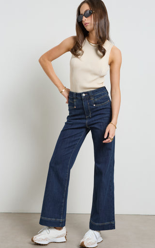 Woman wearing a wide leg Dark Indigo stretch denim jeans standing against a white background