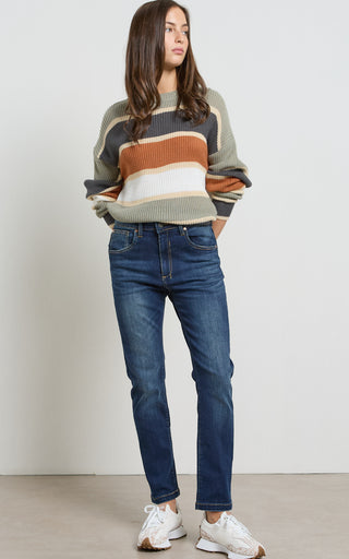 Woman wearing a straight leg Dark Indigo stretch denim jeans standing against a white background