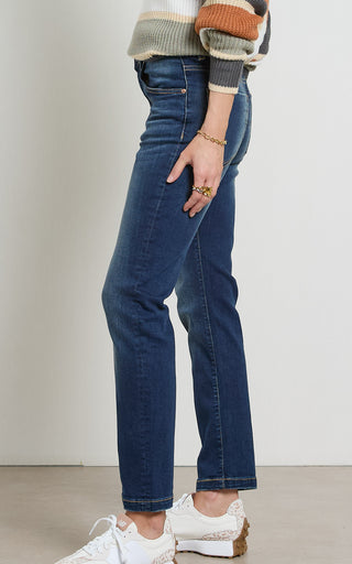 Woman wearing a straight leg Dark Indigo stretch denim jeans standing against a white background