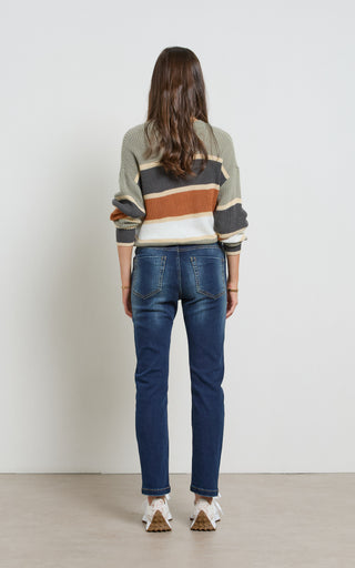 Woman wearing a straight leg Dark Indigo stretch denim jeans standing against a white background