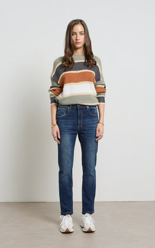 Woman wearing a straight leg Dark Indigo stretch denim jeans standing against a white background