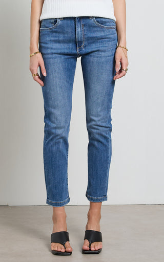 Woman wearing a straight leg Mid blue stretch denim jeans standing against a white background