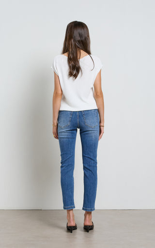 Woman wearing a straight leg Mid blue stretch denim jeans standing against a white background