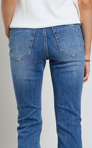 Woman wearing a straight leg Mid blue stretch denim jeans standing against a white background